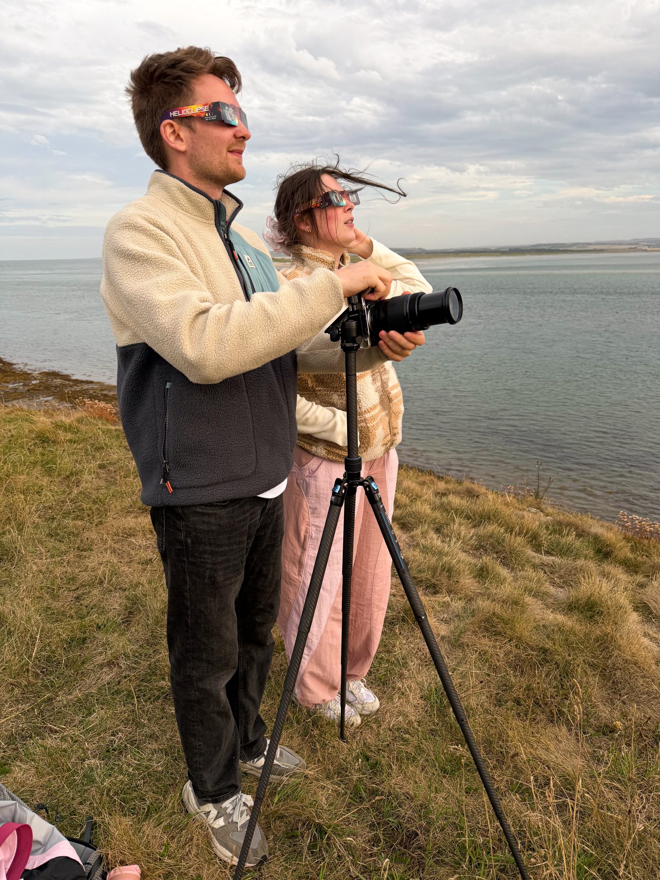 Ellie and Sam beside their camera and tripod on the coast