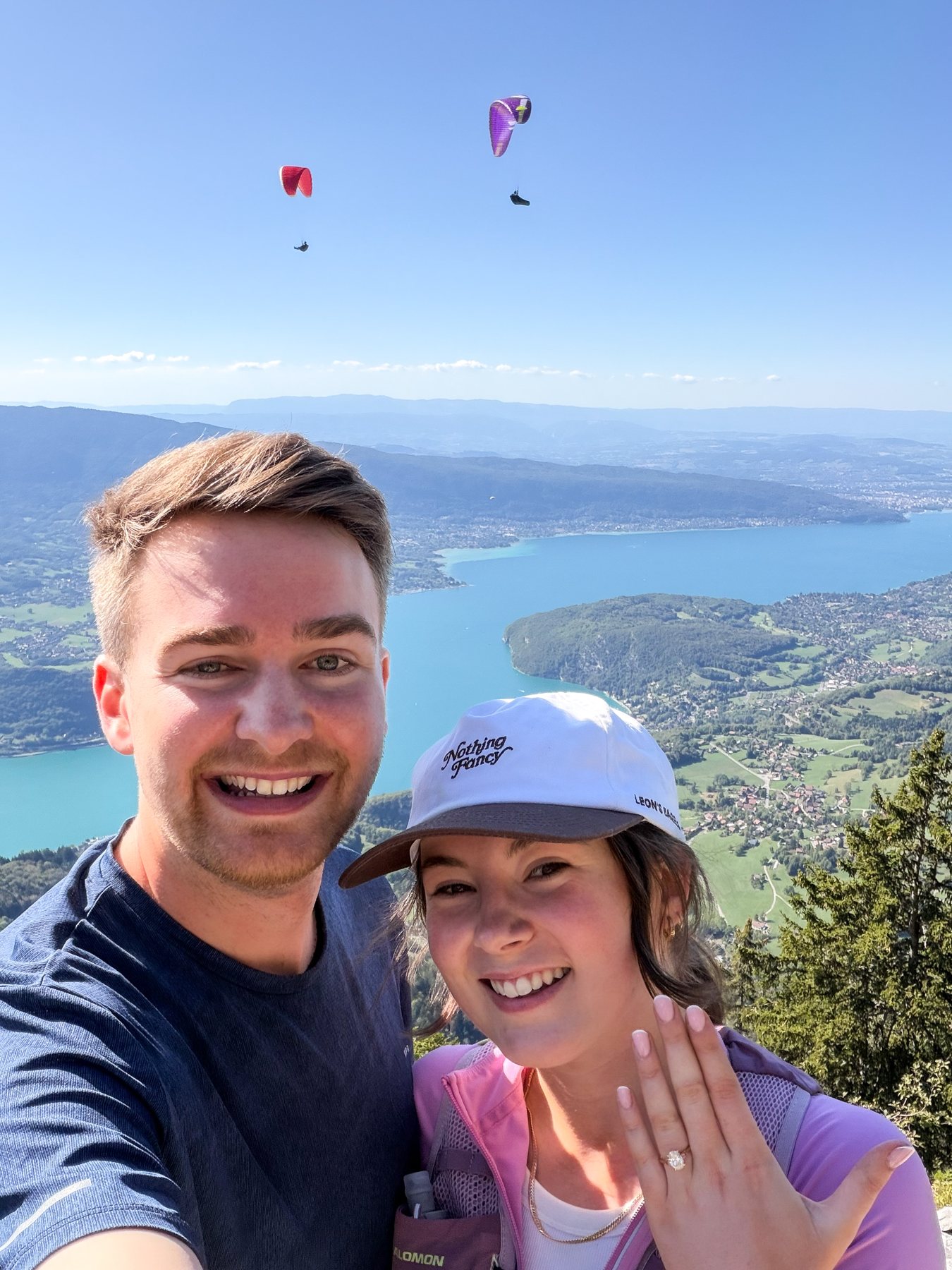 Ellie showing her engagement ring beside Sam above a lake